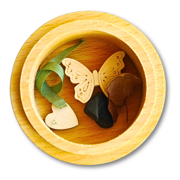 Geöffnete MEMENTOVIA-Box mit Seide, Herz, Obsidian, Schmetterling und Tanne – symbolische Beigaben für Trost, Liebe und Transformation.