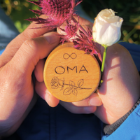 MEMENTOVIA Box in den Händen gehalten mir Gravur Rose und Unendlichkeitsschleife und dem Schriftzug OMA.