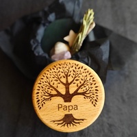 MEMENTOVIA-Box "Ewiges Band" mit Rosenquarz, Stern, Muschel, Eukalyptus und Rosmarin – Beigaben, die Liebe, Treue und die immerwährende Verbindung zum Verstorbenen symbolisieren. Mit Deckel, auf dem ein Baum-Motiv graviert ist, der Schriftzug "Papa" ist zu sehen. Die Beigaben befinden sich in schwarzem Seidenpapier.