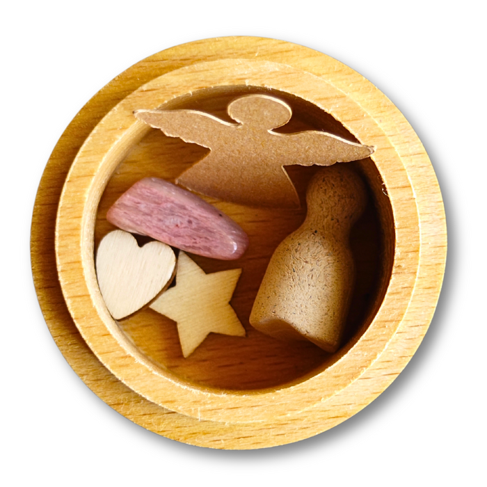 Geöffnete MEMENTOVIA-Box mit Engel, Spielfigur, Stern, Herz und Rhodonit – symbolische Beigaben für Trost, Liebe und bleibende Erinnerung.
